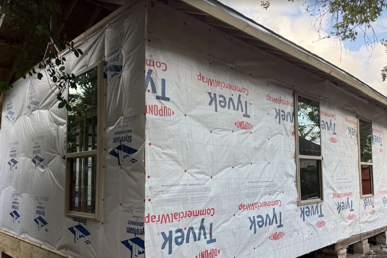 This image captures the critical stage of siding installation where the home is fully wrapped in a weather-resistant barrier, ensuring maximum protection from moisture intrusion.