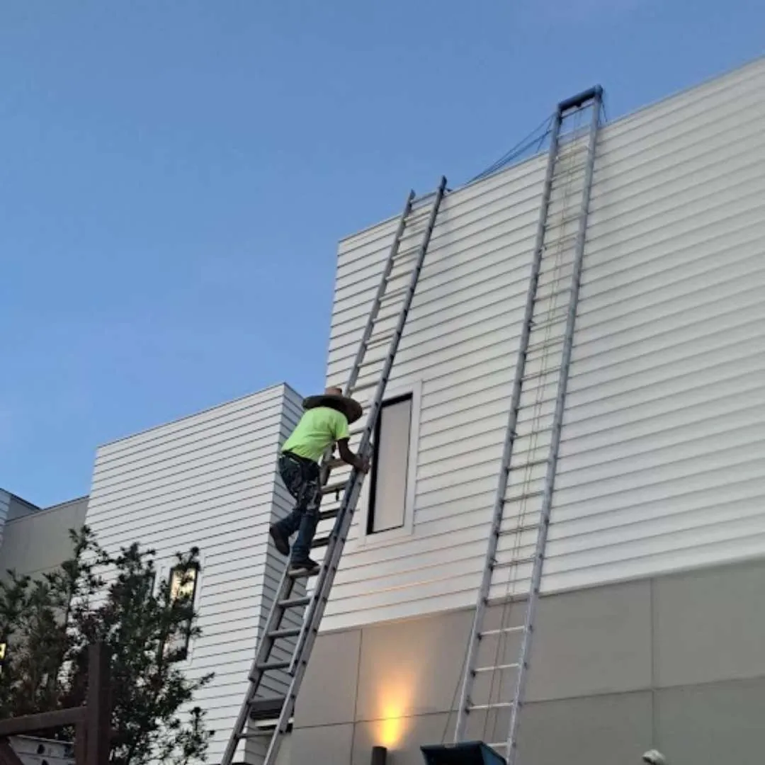 Technician inspecting exterior commercial building wall during a roofing maintenance plan evaluation by Achilles Roofing & Exterior