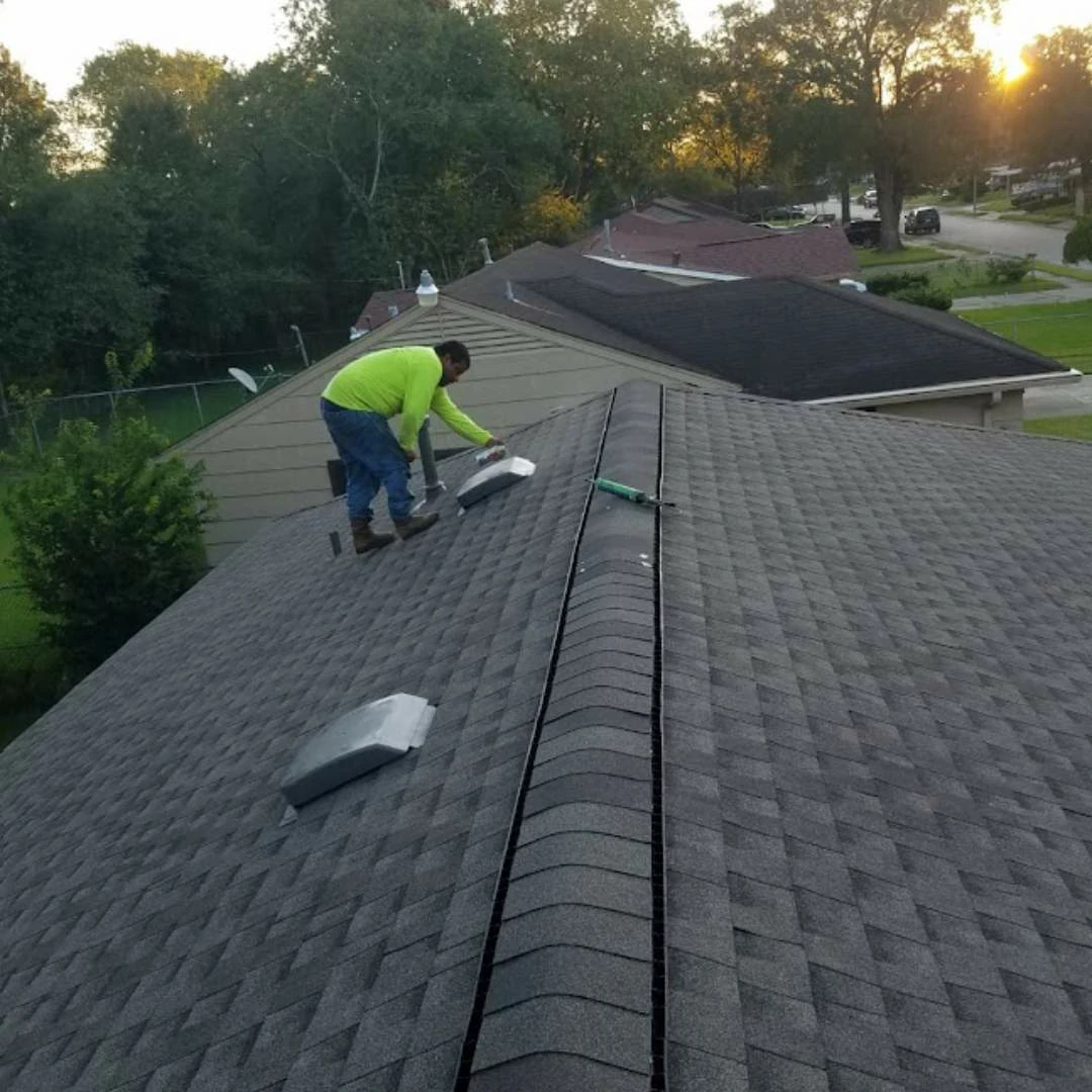 In this image a technician sprays protective coating on a set of metal ventilation units on a flat roof as part of the Maintenance Plan service.