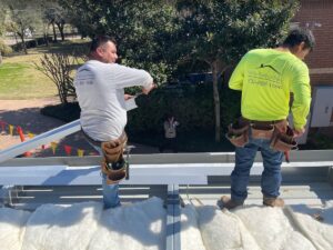 Roofers from Achilles Roofing securing roof panels with precision and care, showcasing the company’s reputation for dependable craftsmanship and as a trusted roofing company.