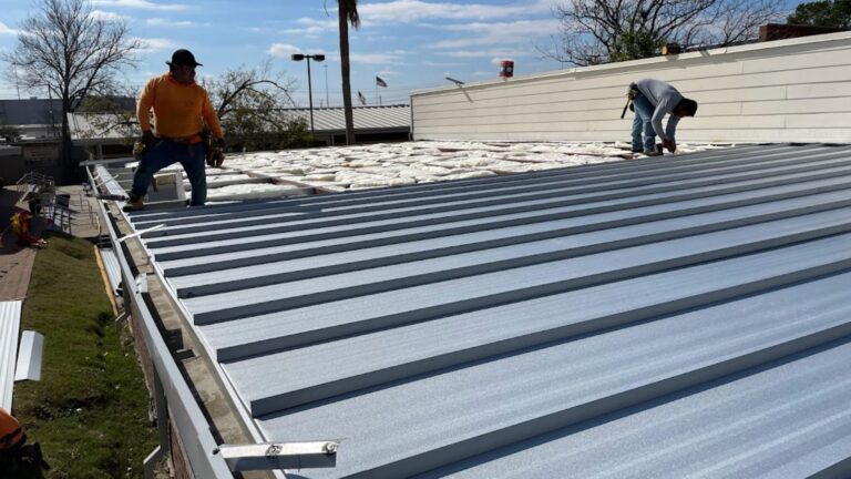 Skilled contractors working on a commercial roof replacement project using premium metal panels for long-term performance.