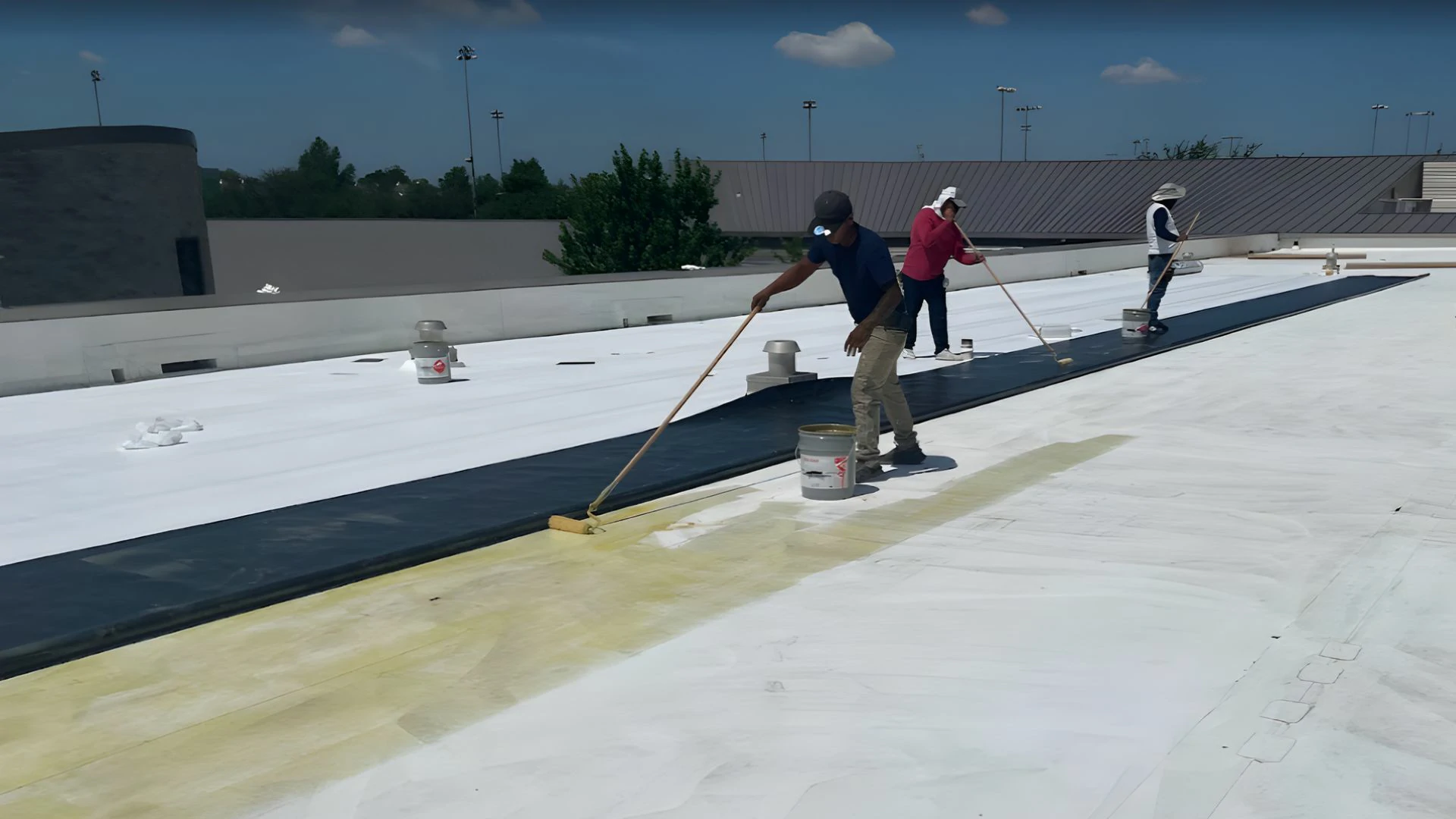 Roofing contractor applying reflective commercial roof coatings on a flat roof deck by Achilles Roofing & Exterior