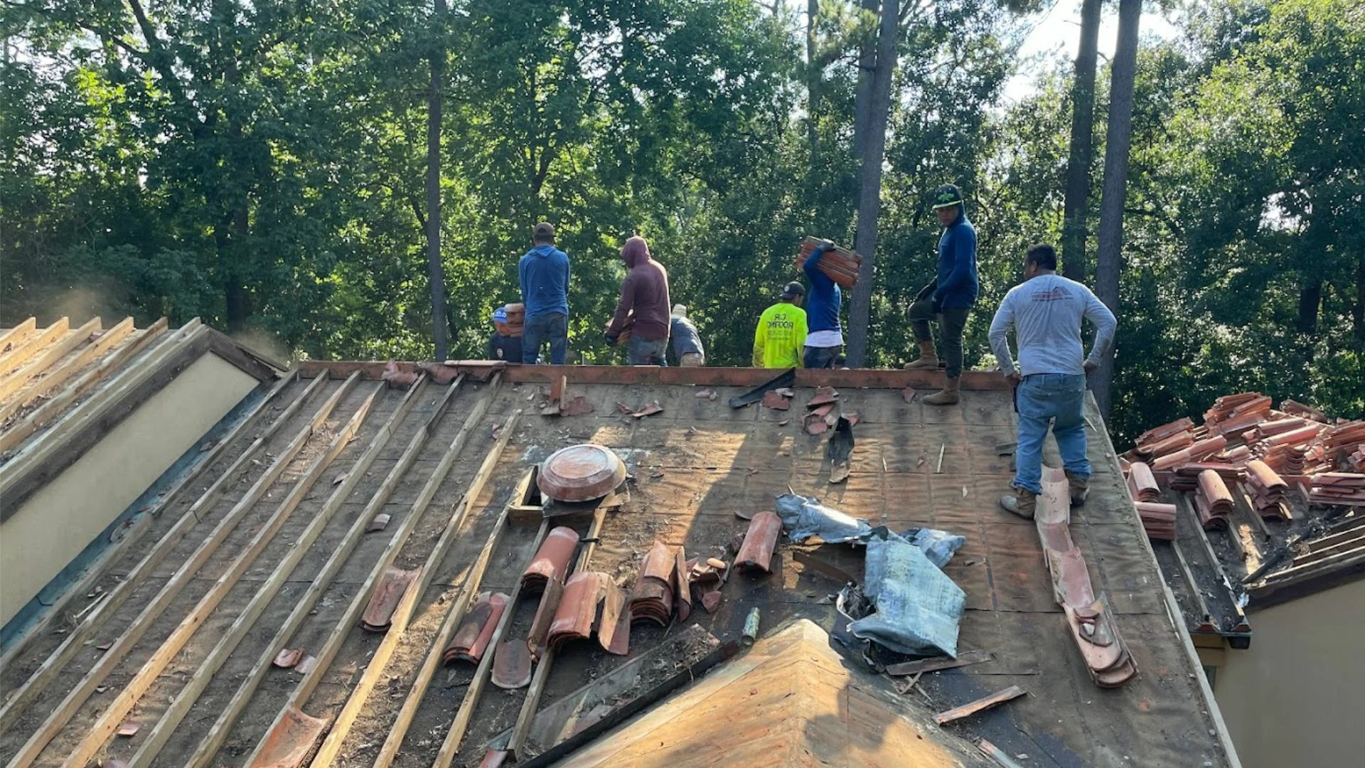 This image shows a roofing crew removing old tiles from a Texas home as they prepare the surface for a fresh installation.