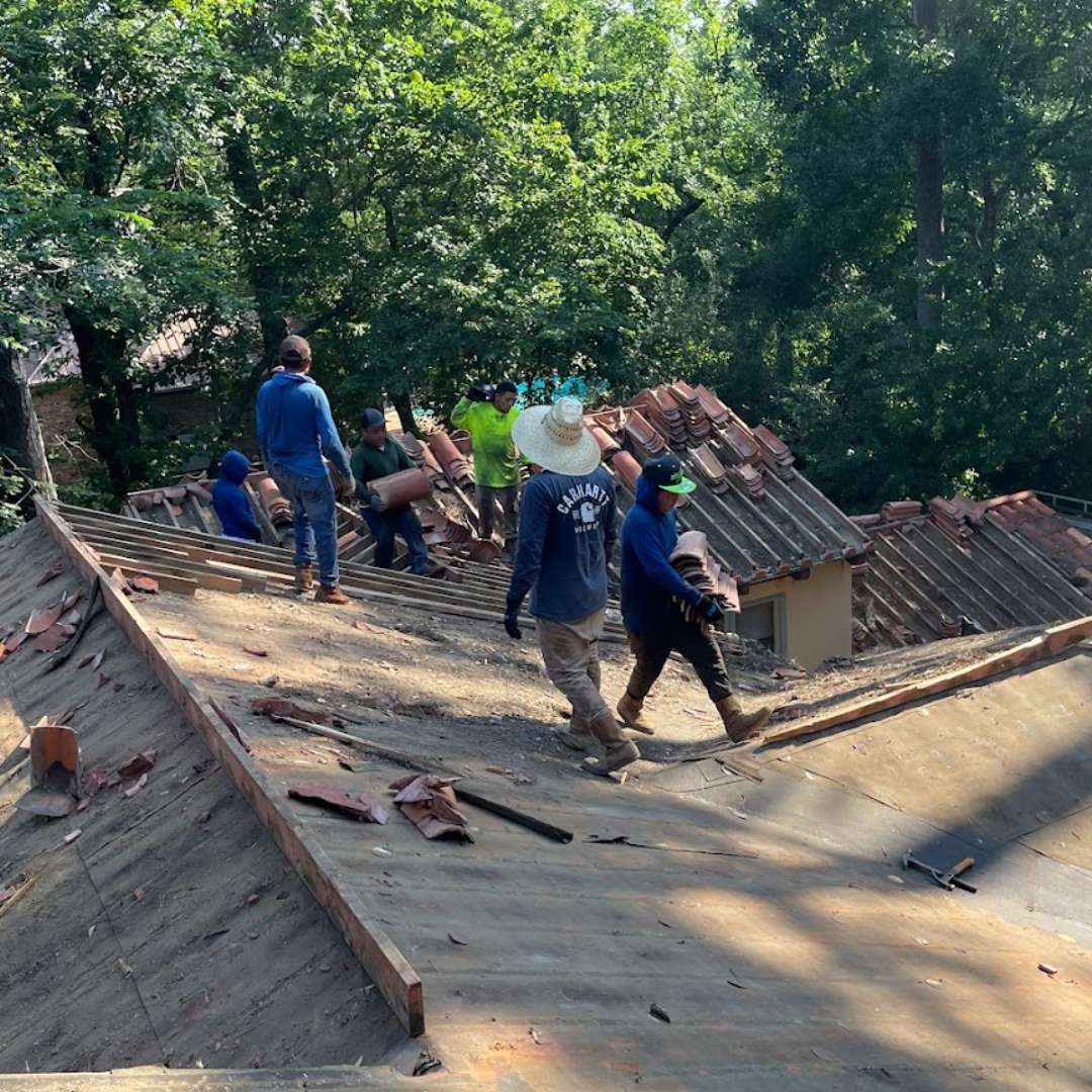 Roofing crew removing damaged clay tiles during a tile roof replacement by Achilles Roofing & Exterior