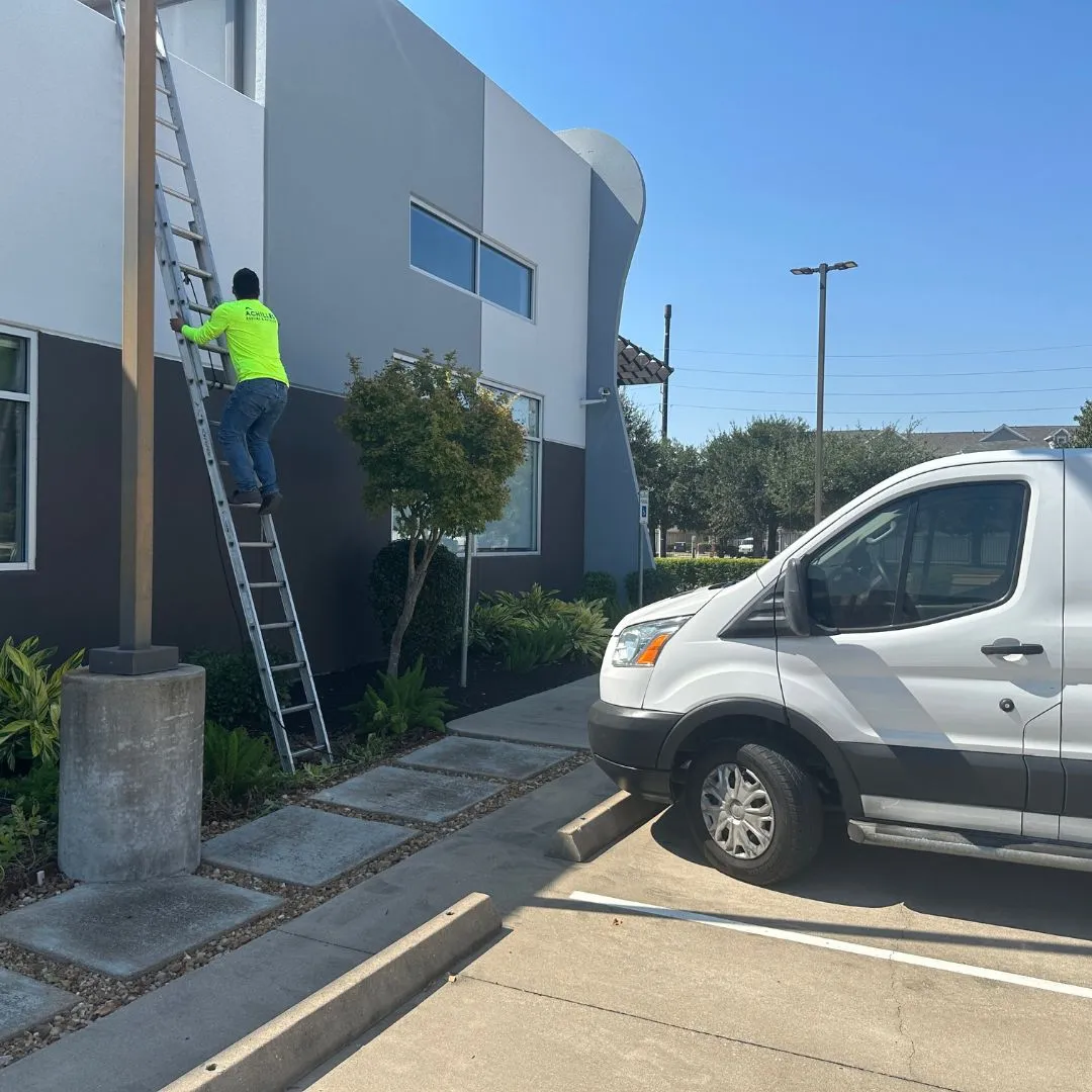 Achilles Roofing & Exterior technician performing a high-reach inspection for a commercial roof replacement in Houston.