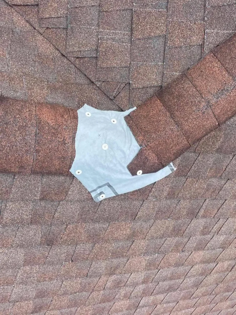 This image shows the roof before repair, with old shingles and an emergency wrap applied — the wear and tear are clearly visible on the roof surface.