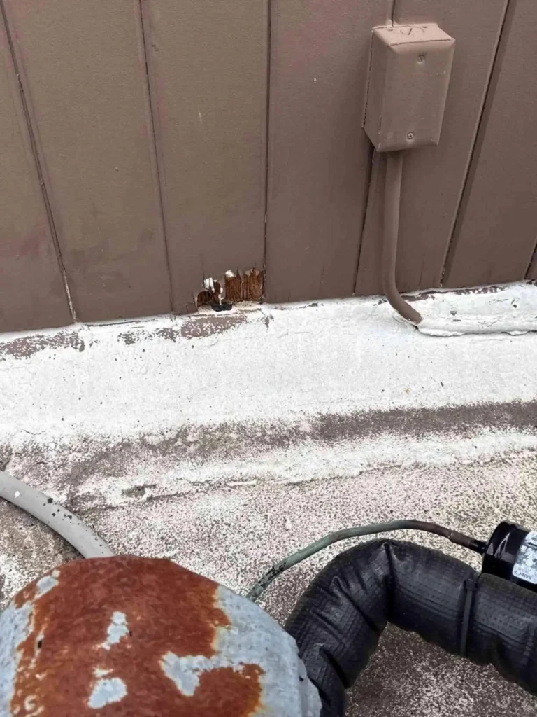 This image shows a Houston, TX home with a significant hole in the siding before any repair work — siding panels are damaged and underlying sheathing is exposed.