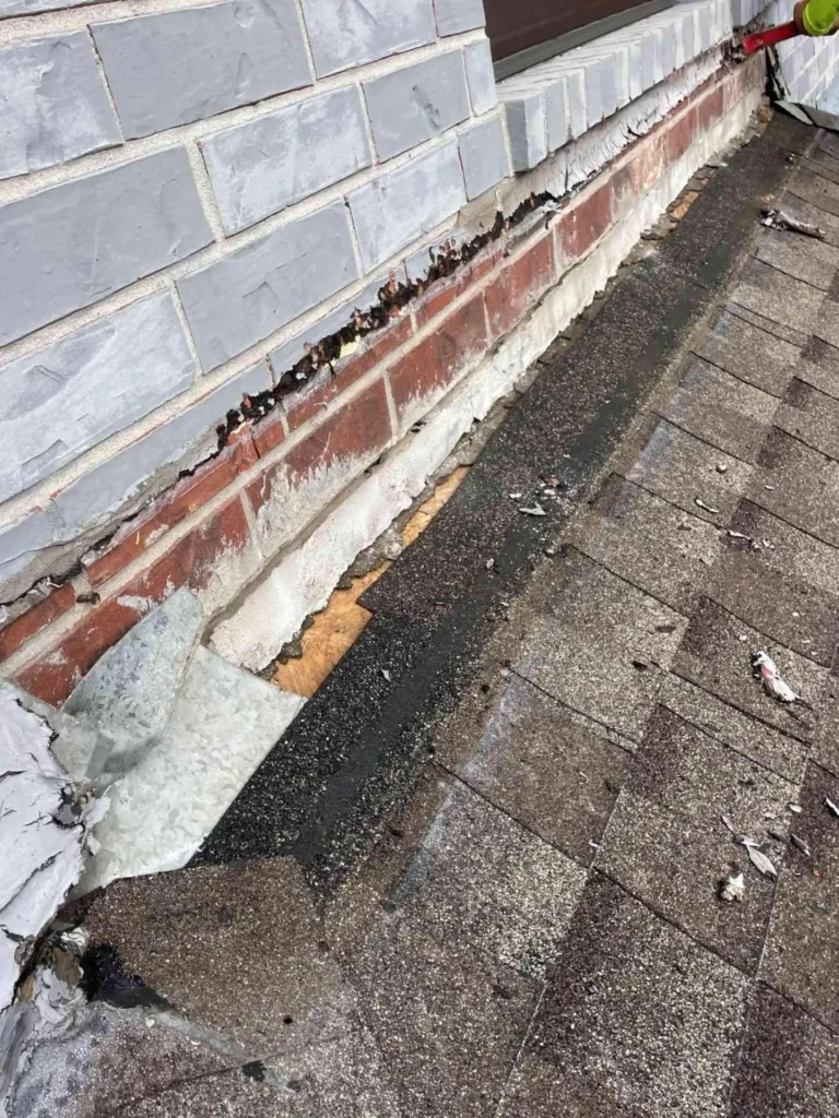This image shows a roof-wall junction on a house in Pasadena, TX where old flashing is exposed — you can see gaps and rust indicating potential leak risks.