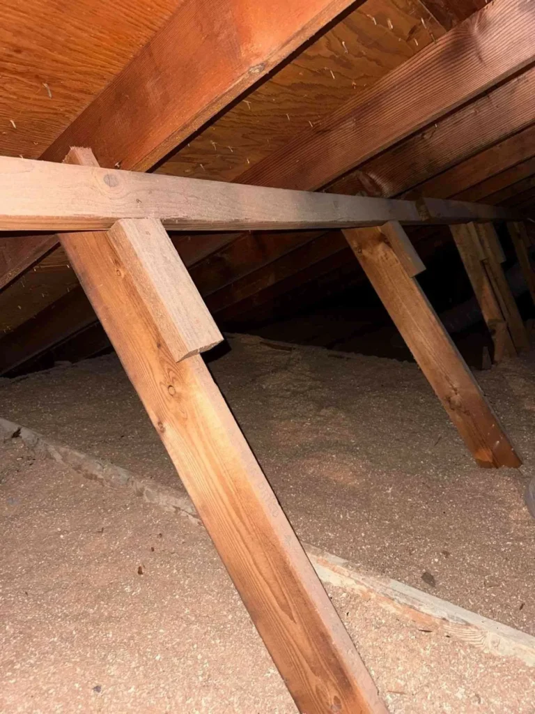 This image shows a freshly repaired wooden rafter inside the attic, with the adjacent soffit boards cleaned and restored to their original condition — highlighting structural recovery and improved ventilation.