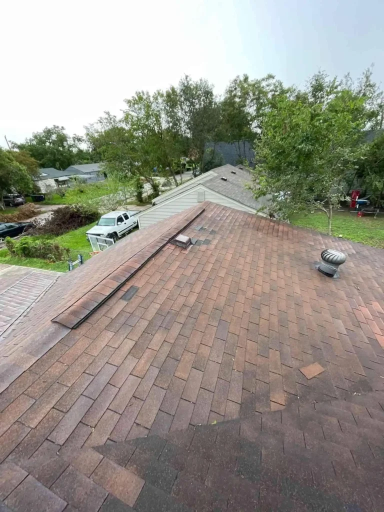 In this photo, missing shingles from storm damage are visible before the Emergency Tarp Installation, demonstrating a proactive step to cover exposed decking and protect interior spaces.