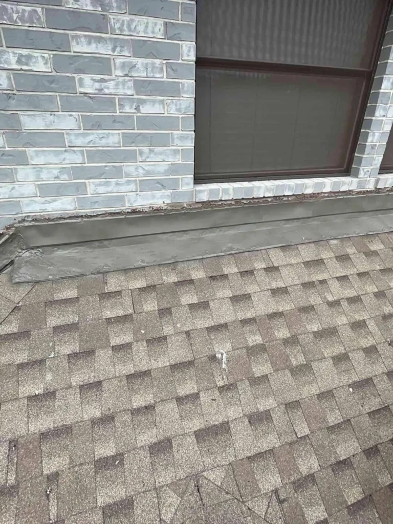 This image shows the freshly completed counter & step flashing replacement at a roof-to-wall junction on a Pasadena, TX home — the metal flashing is properly layered and sealed against the wall.