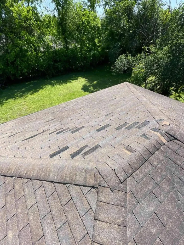 This image shows a broader view of the roof before replacement, revealing multiple areas with missing or damaged shingles, ready for the replacement project.
