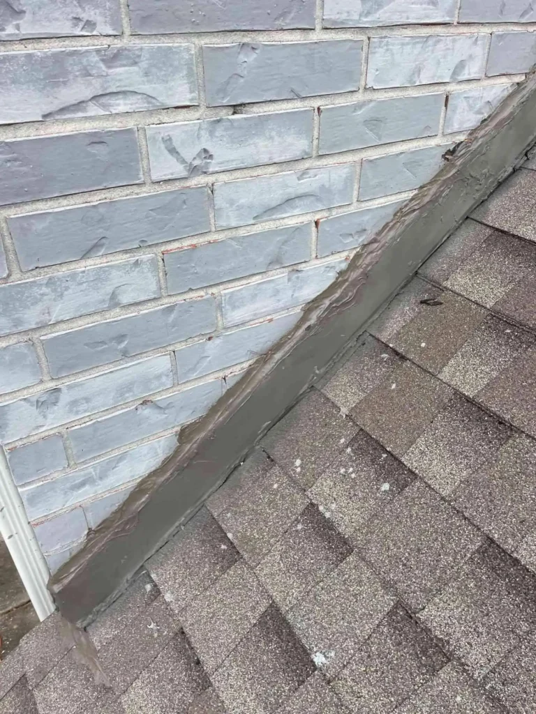 This image shows the replaced counter and step flashing along the joint where the roof meets an exterior wall of a Pasadena, TX home — metal flashings are neatly sealed and aligned for watertight protection.