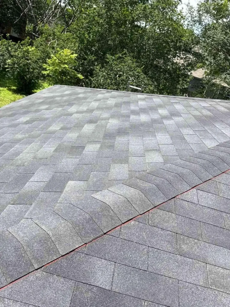 This image shows a Houston home after a completed roof replacement, featuring new asphalt shingles that appear uniform and freshly installed.