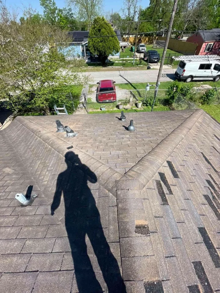 This image shows a Houston home with damaged, worn-out shingles before roof replacement — shingles appear curled and degraded.