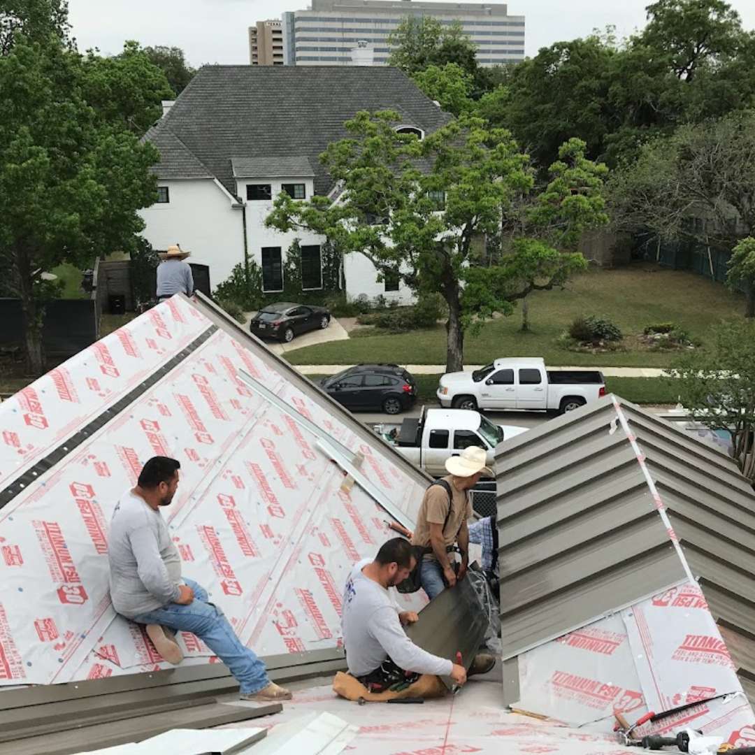 Professional roofing contractors installing metal roofing and protective insulation on a residential roof deck by Achilles Roofing & Exterior