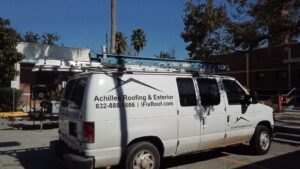 An Achilles Roofing & Exterior service van parked on-site, equipped with ladders and specialized machinery for acrylic roof coating projects.