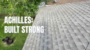 How to Install Architectural Shingles: A broad view of a completed roof under a clear sky, showcasing the thick, dimensional profile of the shingles. Large white text on the left side reads "Achilles: Built Strong," emphasizing the strength of the installation. The uniform pattern reflects the high-quality craftsmanship required when learning how to install architectural shingles.