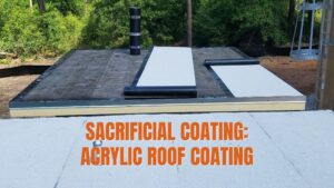 A flat roof under construction showing rolls of membrane being installed alongside a white acrylic roof coating used as a sacrificial protective layer.