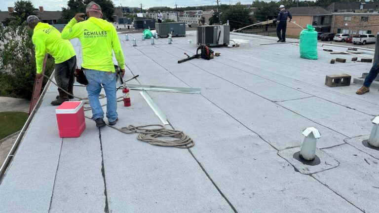 Achilles Roofing Houston specialists executing a low-slope commercial roof installation and safety perimeter check on a flat roof system.
