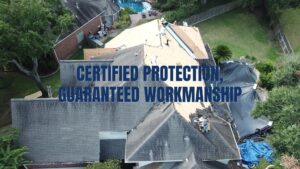 An aerial view of a roofing contractor team performing a full roof tear-off and installation, featuring the text "CERTIFIED PROTECTION, GUARANTEED WORKMANSHIP."
