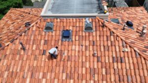 A luxurious residential home featuring a beautifully completed, multi-tiered Spanish tile roof surrounded by green trees.