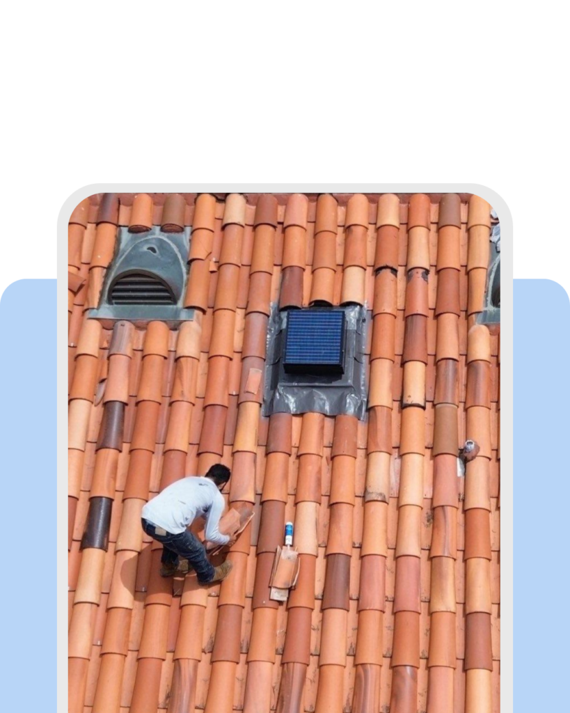 An aerial view captures a skilled technician performing a precise Spanish tile installation on a residential roof, utilizing professional leveling tools and adhesive to ensure a seamless, high-quality clay tile layout.