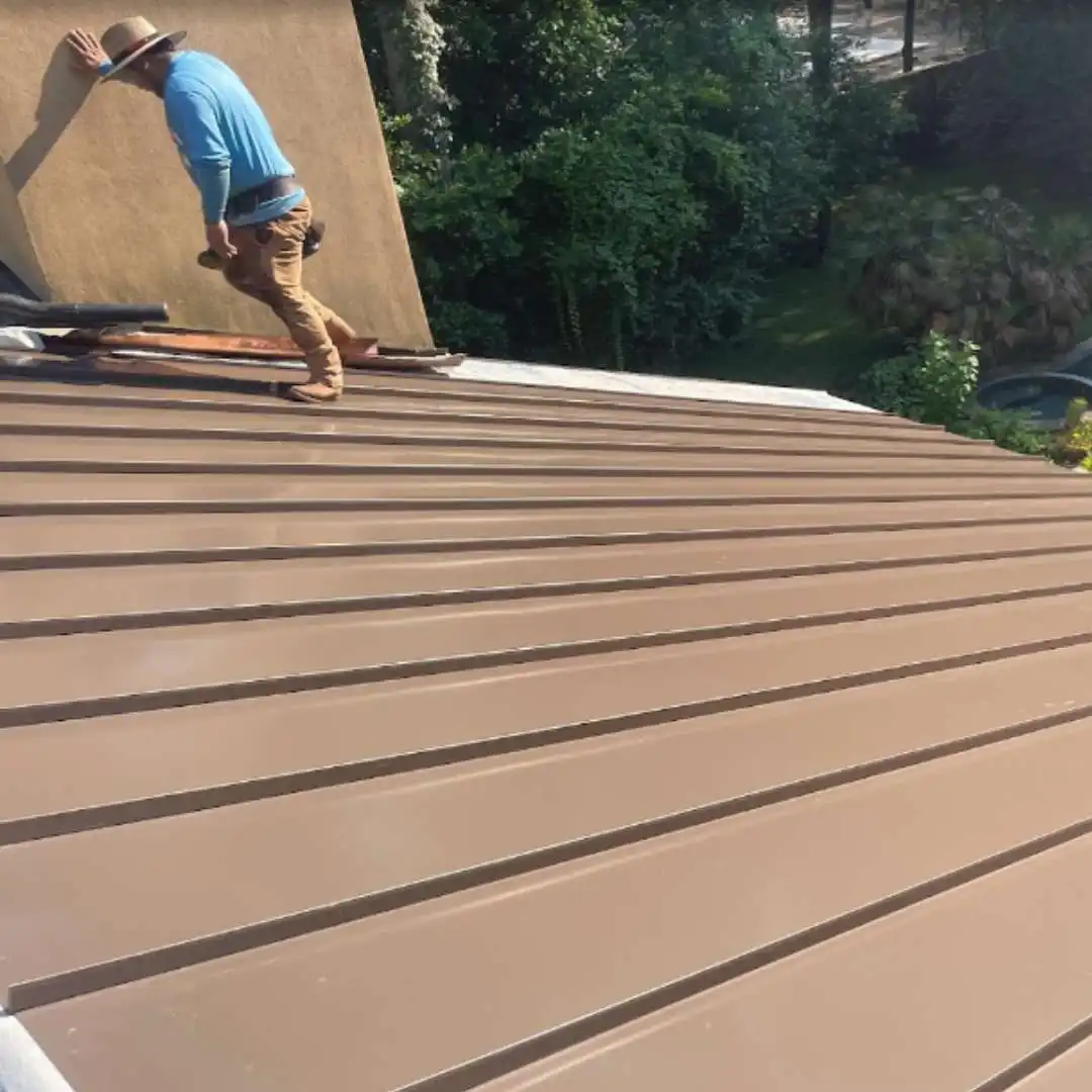 Roofing contractor installing metal roof panels during a metal building re-roof project by Achilles Roofing & Exterior