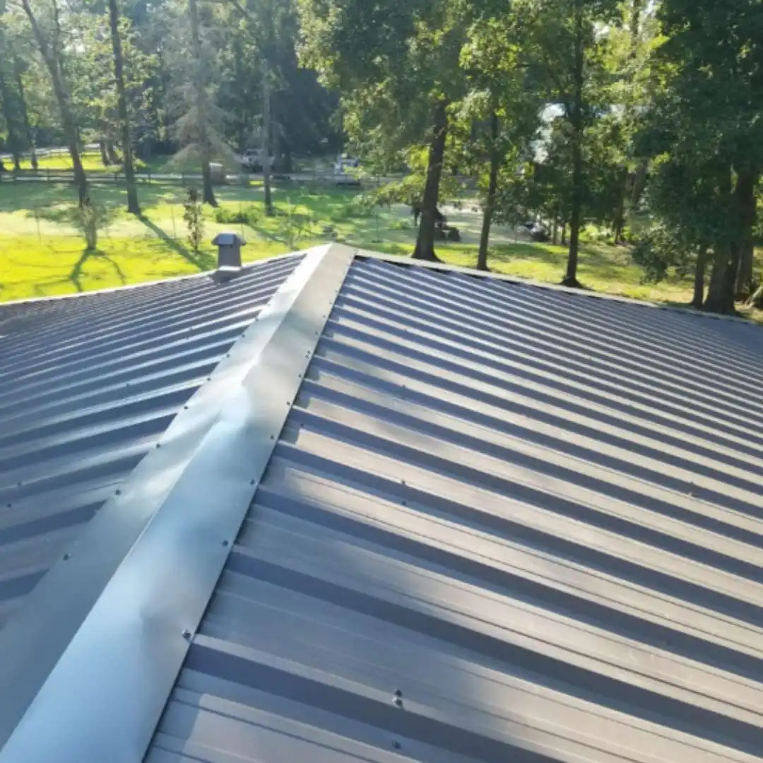 Blue R-panel metal roofing installation and ridge cap detailing during a metal building re-roof project by Achilles Roofing & Exterior