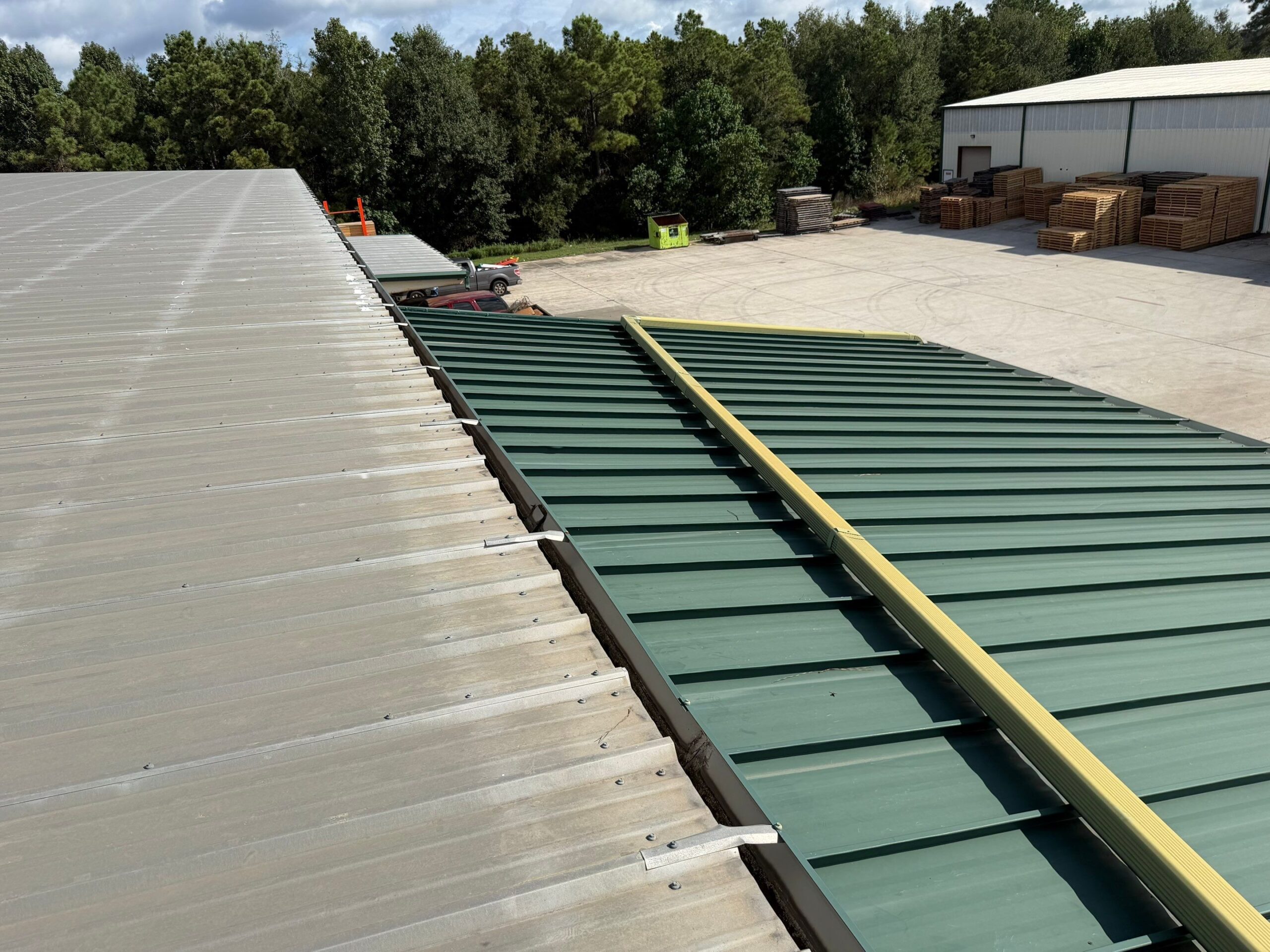 Side-by-side view comparing exposed fastener roofing with a clean green standing seam metal roof installed on a commercial facility, by Achilles.